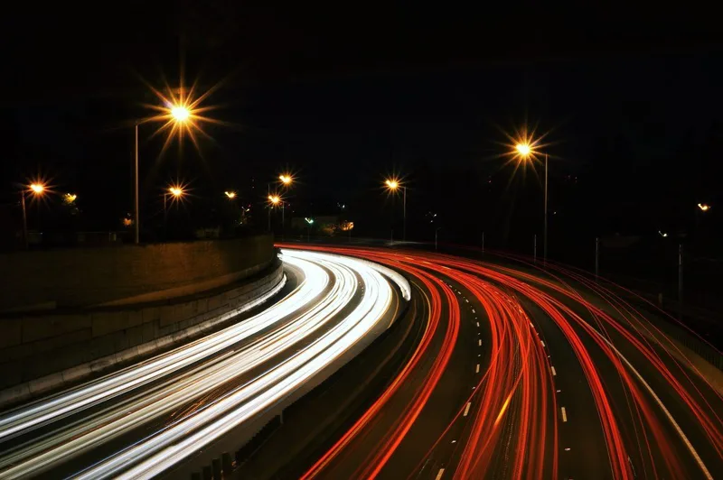 夜の高速道路を流れる車のライトの軌跡の写真