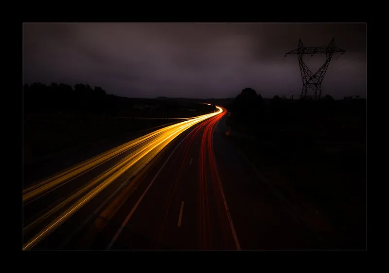 夜の道路に車のライトが光の筋になって延びる写真